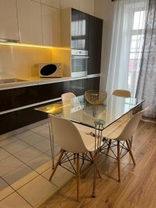 cocina con mesa de cristal y sillas en Near Station Apartment, en Vilna