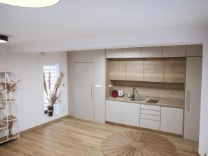 a kitchen with white cabinets and a wooden floor at Ateliér Smutná in Ostrava