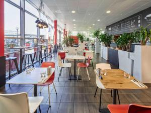 a restaurant with tables and chairs and windows at ibis Paris CDG Airport in Roissy-en-France
