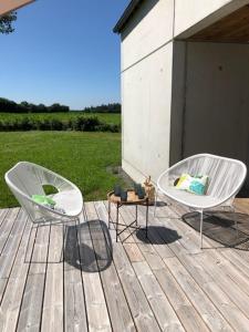 2 sillas blancas sentadas en una terraza de madera en House for 4 persons 10 minutes from Paimpol., en Plourivo