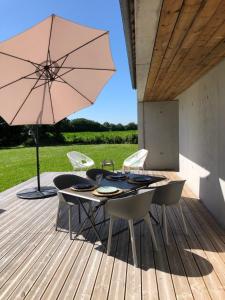 einen Tisch und Stühle mit einem Sonnenschirm auf einer Terrasse in der Unterkunft House for 4 persons 10 minutes from Paimpol. in Plourivo