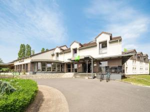 una gran casa blanca con una bicicleta estacionada en la entrada en ibis Styles Sarrebourg, en Sarrebourg