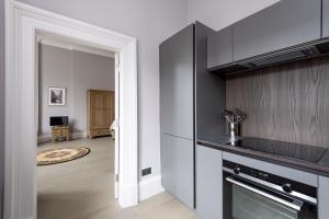 a kitchen with a stove top oven next to a living room at Modern George Street Studio sleeping 2 in Edinburgh