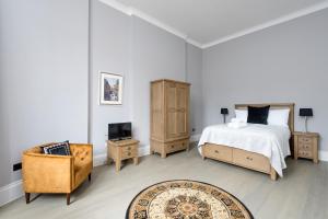 ein Schlafzimmer mit einem Bett, einem Stuhl und einem TV in der Unterkunft Modern George Street Studio sleeping 2 in Edinburgh