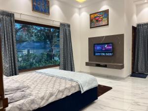 a bedroom with a bed and a flat screen tv at The Green Wood Palace I Farm House I wedding I Party I 87oo2o5865 in Gurgaon