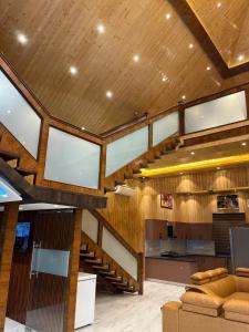 a living room with a wooden ceiling and a staircase at The Green Wood Palace I Farm House I wedding I Party I 87oo2o5865 in Gurgaon