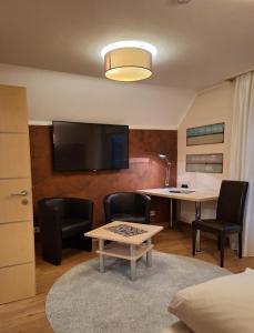 a living room with a table and chairs and a tv at Hotel Garni Pension Zur Krone in Hilpoltstein