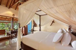 a bedroom with a white bed with a canopy at Villa Patria in Lovina