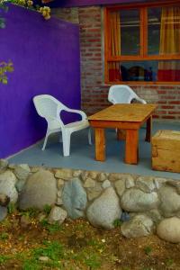 two white chairs and a wooden table and a purple wall at Cabañas Las Violetas Patagonia in El Bolsón +2 photos