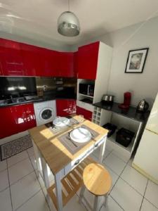 cocina con armarios rojos y mesa de madera en L'aviateur - self check in, en Chartres