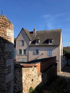 una gran casa blanca sentada detrás de una pared de ladrillo en L'aviateur - self check in, en Chartres