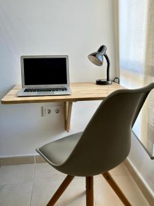 un ordenador portátil sentado en un escritorio de madera con una silla en Apartamento La Calma, en Lliber