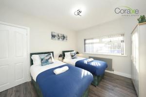 2 camas con colchas azules en una habitación en 3 Bedroom Tranquil Haven for Contractors and Families by Coraxe Short Stays, en Old Hill