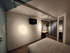 um quarto com uma cama e uma televisão na parede em ibis budget Chambourcy Saint Germain em Chambourcy