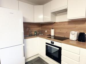 a kitchen with white cabinets and a black appliance at L'Estival - Free parking in Mainvilliers