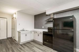 a kitchen with white cabinets and a black refrigerator at La Quinta by Wyndham Lexington Park - Patuxent in California