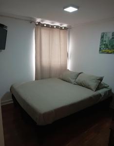 uma cama num quarto com uma parede branca em Hospedaje GYT Caldera em Caldera