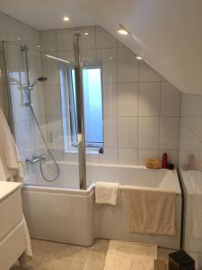 een badkamer met een douche en een bad met een raam bij Idyllisk sørlandshus in Risør