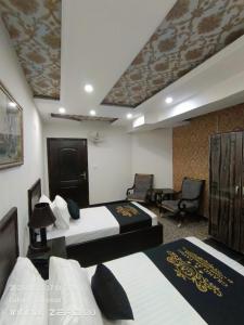 um quarto de hotel com duas camas e duas cadeiras em Grand AlFateh Hotel em Lahore