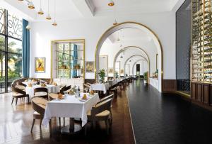 富國的住宿－Wyndham Grand Phu Quoc，餐厅设有白色的桌椅和窗户。