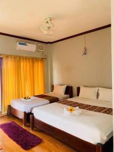 una camera d'albergo con due letti con fiori di Inthila Garden Guest House a Vang Vieng