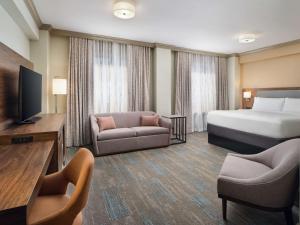 une chambre d'hôtel avec un lit, un canapé et une télévision dans l'établissement Hampton Inn & Suites New Orleans Canal St. French Quarter, à La Nouvelle-Orléans