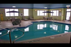 a pool in a hotel with tables and chairs at Wingate by Wyndham Kittanning in Kittanning