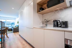 a kitchen with white cabinets and a dining room at Trindade Bliss: 1BR w/ Free Parking by LovelyStay in Porto