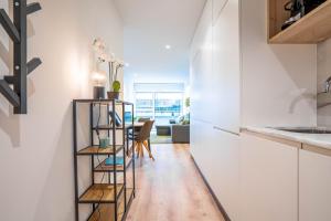a kitchen with white cabinets and a wooden floor at Trindade Bliss: 1BR w/ Free Parking by LovelyStay in Porto