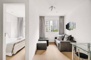 a white bedroom with a bed and a couch at Suítes Inside Windham Sao Paulo Paulista in Sao Paulo
