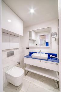 a white bathroom with a toilet and a sink at Panorama Sea View Central City Batumi & ApartHOTEL in Batumi