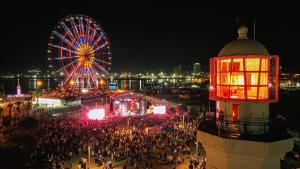 a crowd of people at a carnival with a ferris wheel at Panorama Sea View Central City Batumi & ApartHOTEL in Batumi
