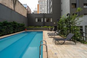 - une piscine avec 2 chaises longues à côté d'un bâtiment dans l'établissement Suítes Inside Windham Sao Paulo Paulista, à São Paulo