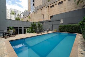 a large blue swimming pool in front of a building at Suítes Inside Windham Sao Paulo Paulista in Sao Paulo