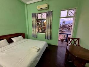 ein grünes Schlafzimmer mit einem Bett und einem Fenster in der Unterkunft KFG Guesthouse in Thakhek