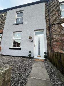una porta bianca su una casa di mattoni con due piante di Cosy home perfect for families and contractors a Darlington