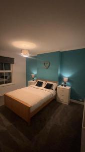 um quarto com uma cama grande e uma parede azul em Cosy home perfect for families and contractors em Darlington