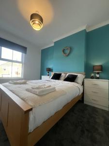 a bedroom with a large bed with a blue wall at Cosy home perfect for families and contractors in Darlington