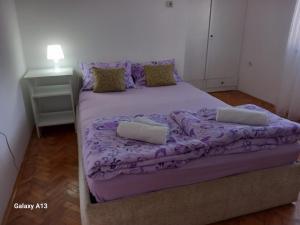 Bett in einem Zimmer mit lila Bettwäsche und Kissen in der Unterkunft Apartmani Pavlov in Aranđelovac