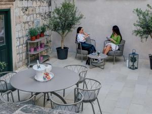 two women sitting on a patio with tables and chairs at Tailor Apartment with a Private Terrace in Dubrovnik +11 photos