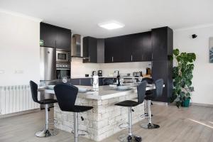 a kitchen with black cabinets and black bar stools at Villa Colina in Salir de Matos