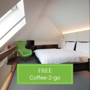 1 dormitorio con cama, escritorio y silla verde en b-smart motel Basel, en Basilea