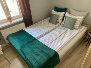 a bed in a bedroom with a green blanket on it at Apartament Sunset in Sopot