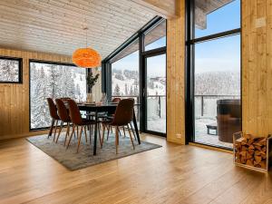 uma sala de jantar com mesa, cadeiras e janelas em Ski-in-out hytte på Kvitfjell em Strande