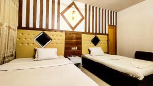 a room with two beds and a chair in it at White Rose Suites Ltd in Dhaka