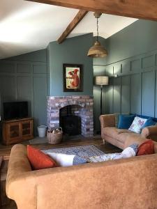 sala de estar con 2 sofás y chimenea en The Nut House - Squirrel Lane Lodges Ludlow en Ludlow