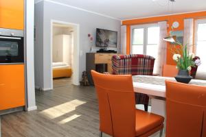 una sala da pranzo con pareti arancioni e tavolo e sedie di Haus Sonne a Thiessow