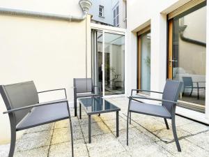 2 chaises et une table en verre sur la terrasse dans l'établissement Le Patio de la Reine Berthe - Parking Included, à Chartres