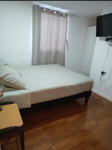 a small bedroom with a bed with a window at Hospedaje GYT Caldera in Caldera