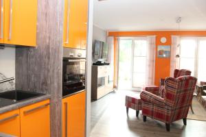 una cucina con armadi arancioni e un soggiorno di Haus Sonne a Thiessow